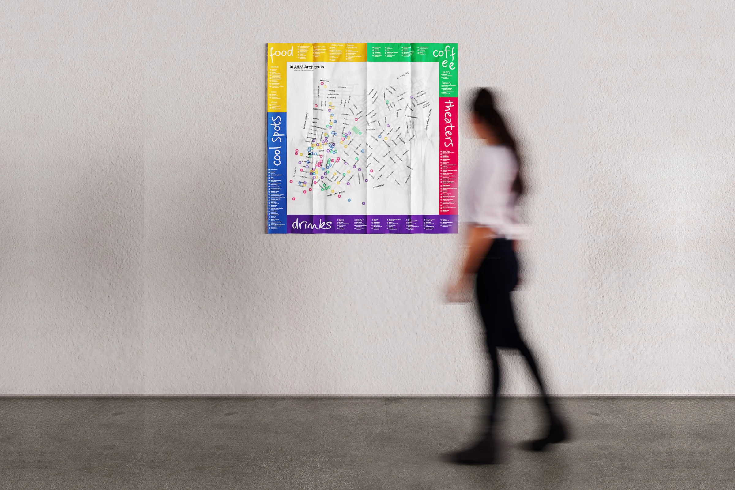 A woman walking past the Our Kypseli map hanging unfolded on a white wall